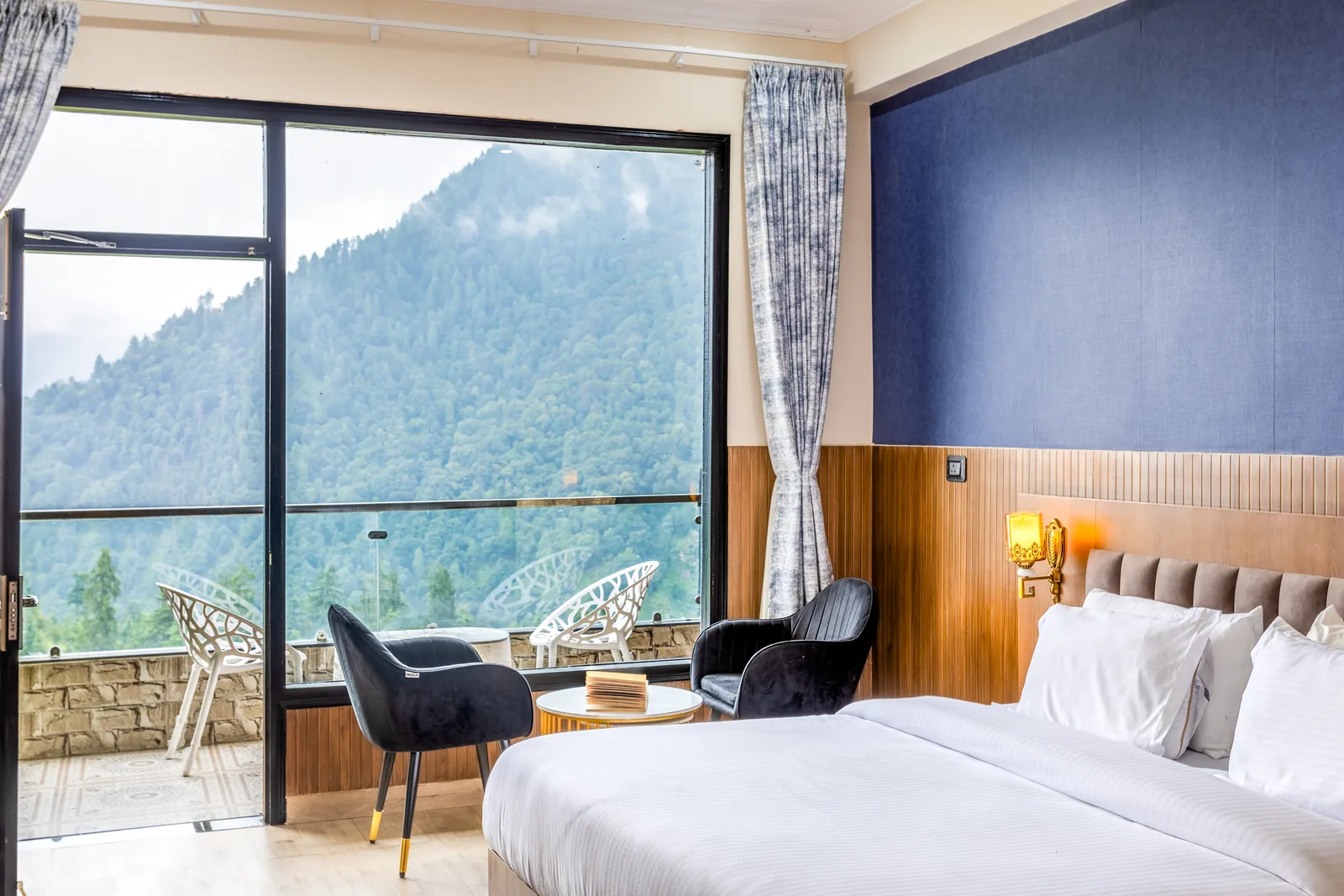 Meadow Suite — bed with the balcony chairs and mountains behind